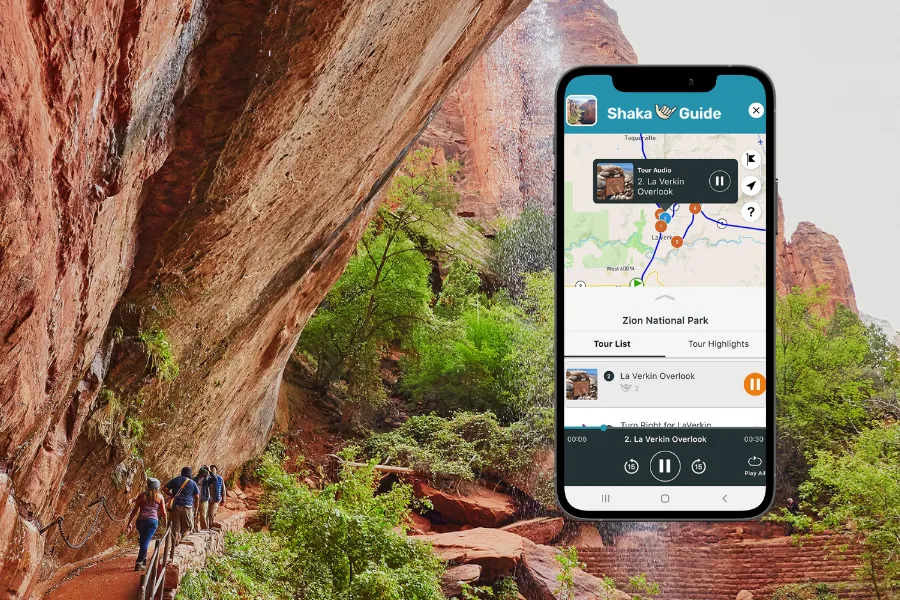 Smartphone displaying the Shaka Guide app beside a steep red rock canyon trail with hikers, greenery, and towering sandstone walls.