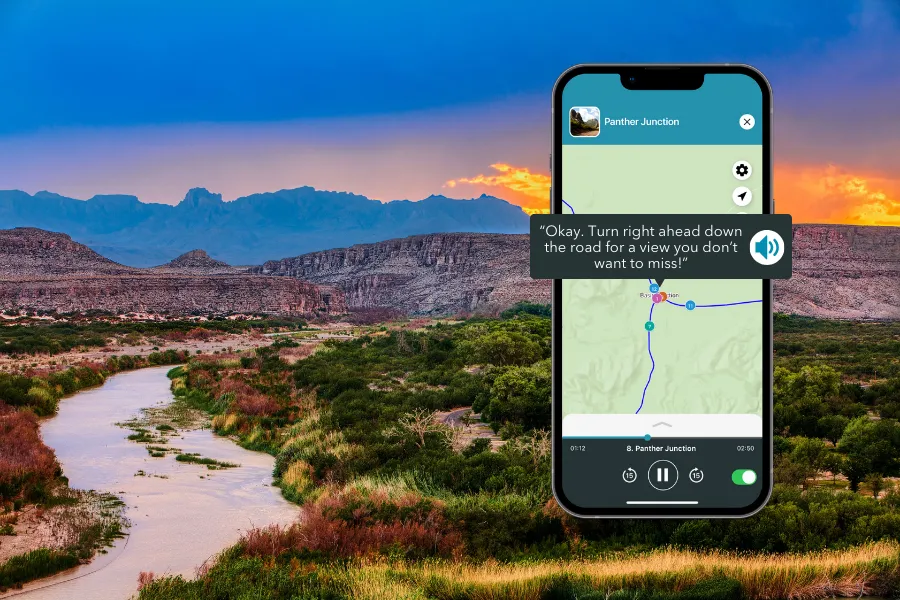 Smartphone displaying the Shaka Guide app over a winding river landscape with desert mountains, green brush, and a glowing sunset sky.