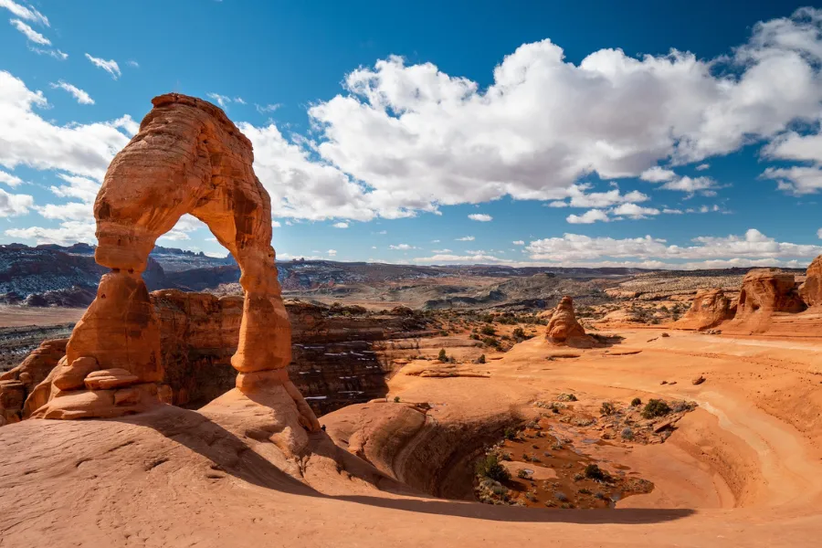 Delicate Arch standing tall against a backdrop of desert and distant mountains in Utah.