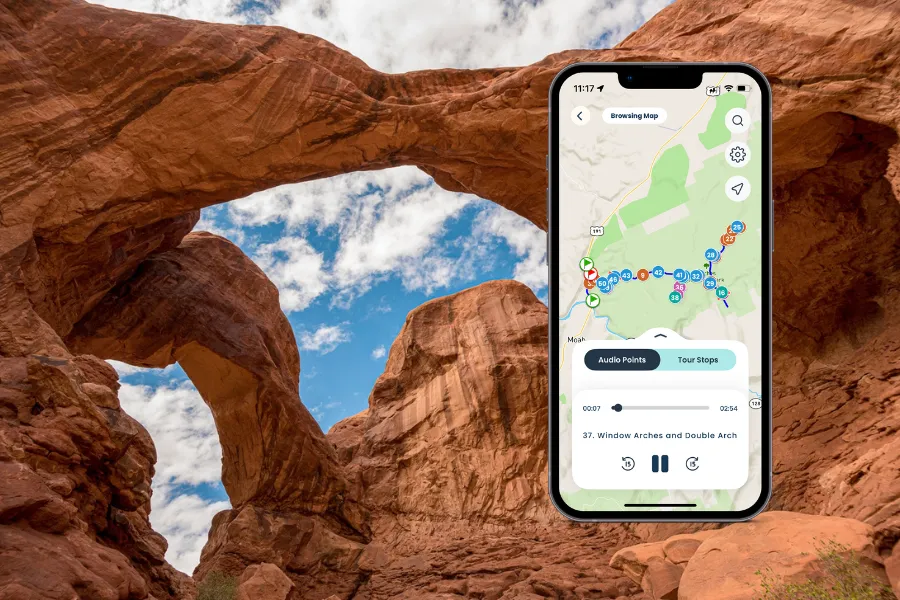 Double Arch in Arches National Park with a smartphone showing the Shaka Guide app.