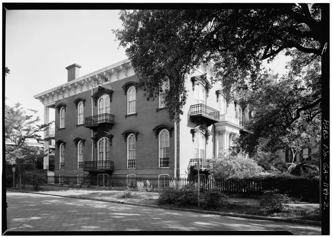 Historic Mercer-Williams House viewed from the street, showcasing its distinctive architectural features and surrounding greenery.