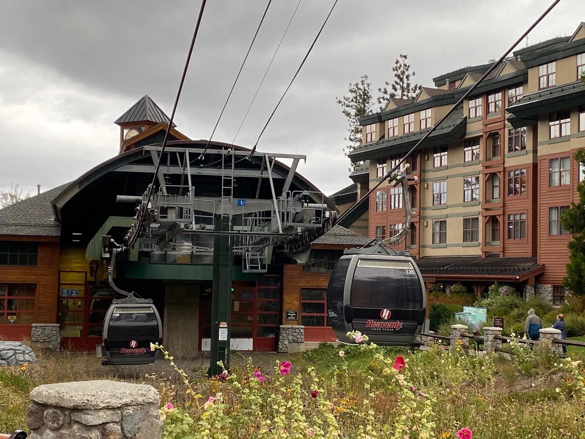 ondola cabins at Heavenly Ski Resort station with surrounding lodge buildings, flowers, and cloudy mountain atmosphere.