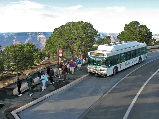 Visitors disembark from a Grand Canyon shuttle bus on the scenic Red Route, ready to explore the South Rim.