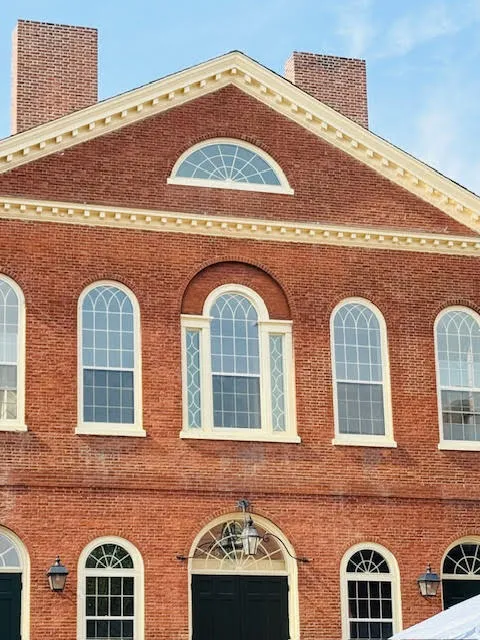 Brick facade of Salem’s Old Town Hall with arched windows and white trim against a blue sky backdrop.