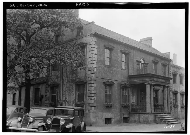 Historic view of The Olde Pink House in Savannah, featuring its architectural details and surrounding trees.