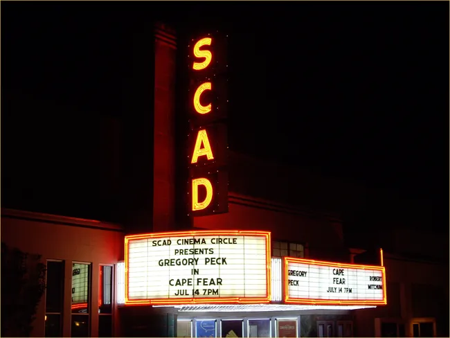 Historic SCAD Theatre marquee showcasing a film screening, illuminated at night.
