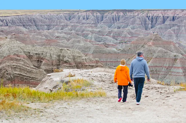 Visitors walking along a trail with colorful rock formations in Badlands National Park, South Dakota.