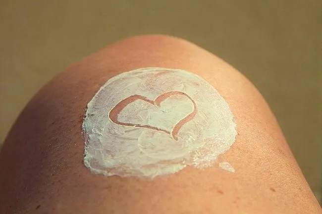 Heart shape drawn in sunscreen lotion on a person’s sun-kissed shoulder.