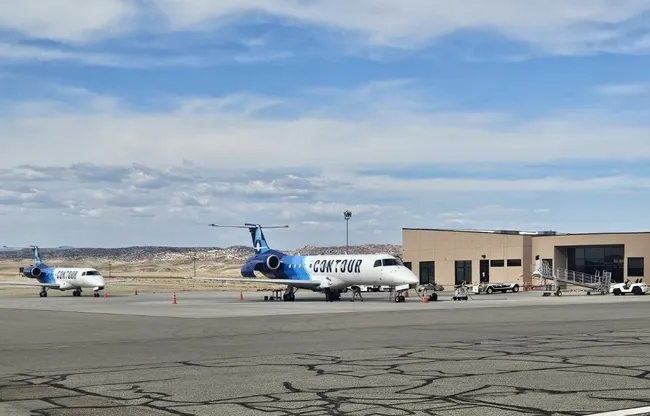 Contour Airlines planes parked at the terminal of Canyonlands Regional Airport under a partly cloudy sky.