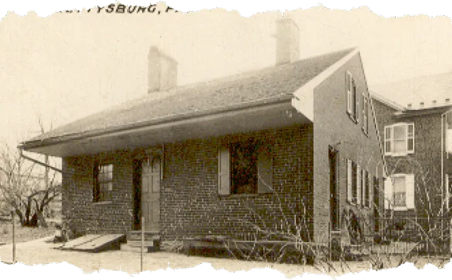 Sepia-toned photo of an old brick house with chimneys and wooden shutters, showing a worn vintage texture.