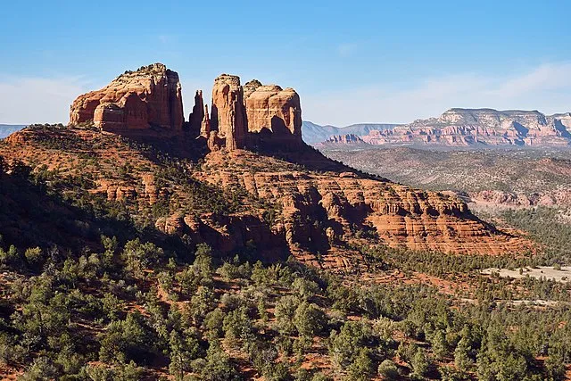 A panoramic view of Cathedral Rock in Sedona, Arizona, with red sandstone formations and desert vegetation.