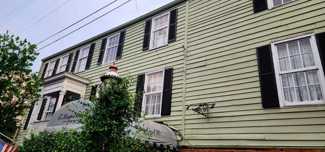 The exterior of the 1790 Inn, featuring green siding, black shutters, and a decorative entrance.