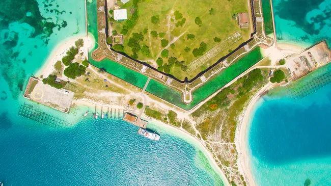 erial view of Garden Key at Dry Tortugas National Park, showcasing Fort Jefferson, turquoise waters, and a docked ferry.