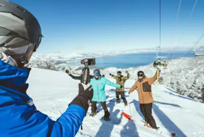Group of skiers posing for a photo on a snowy mountain with Lake Tahoe in the background.