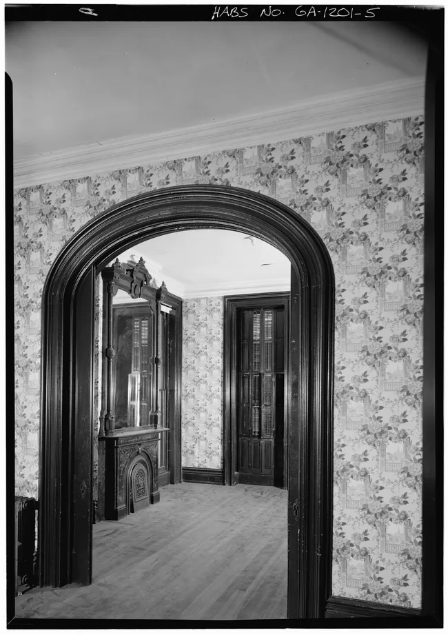 Interior view of the Hamilton-Turner Inn, showcasing archways and ornate furnishings against floral wallpaper.