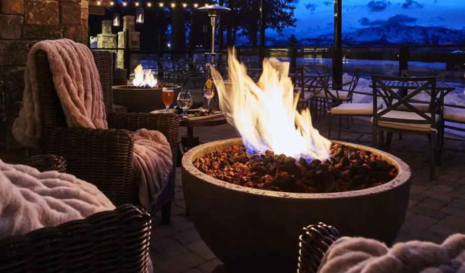 Lakeside dining setup with cozy chairs, blankets, and a fire pit, creating an inviting evening atmosphere at a restaurant in South Lake Tahoe.