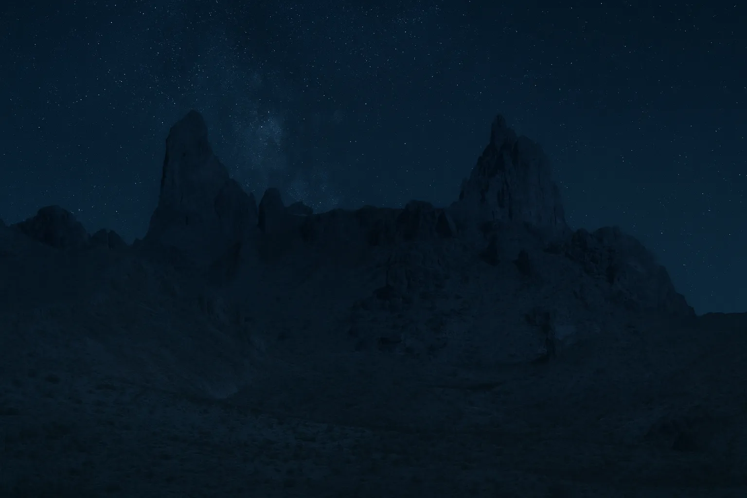Dark silhouette of jagged mountain peaks under a starry night sky in Big Bend National Park.