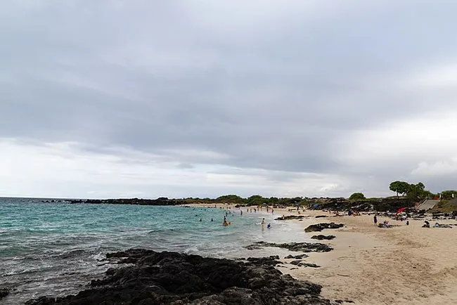 white sand beach with people sand bathing in big island