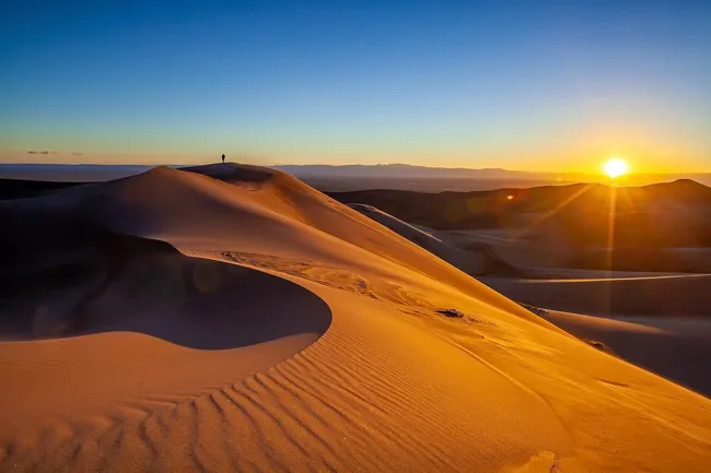 Golden sand dunes glow under a vibrant sunrise at Great Sand Dunes National Park.