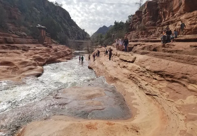 Visitors enjoy walking along the natural water slide and red rock formations at Slide Rock State Park.