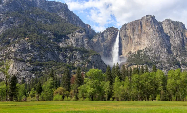 A powerful stream of water tumbles down Bridalveil Fall, framed by granite cliffs and lush green forest.