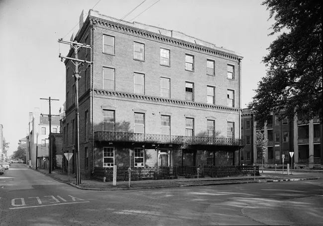 Historic Marshall House exterior view on a street corner, showcasing its brick architecture and wrought-iron balcony.