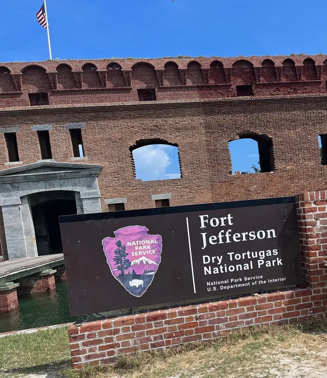 Entrance sign for Fort Jefferson at Dry Tortugas National Park with historic brick walls in the background.