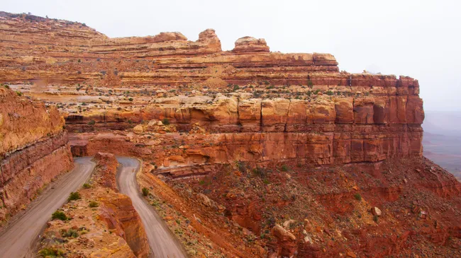Winding dirt road carved into steep red rock cliffs along the Moki Dugway in Utah’s desert.