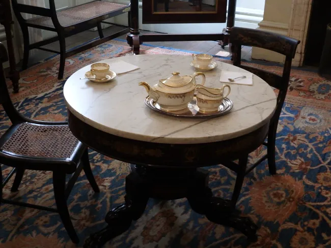 A marble-topped table set with teacups and a teapot in a historic room at the Owens-Thomas House.