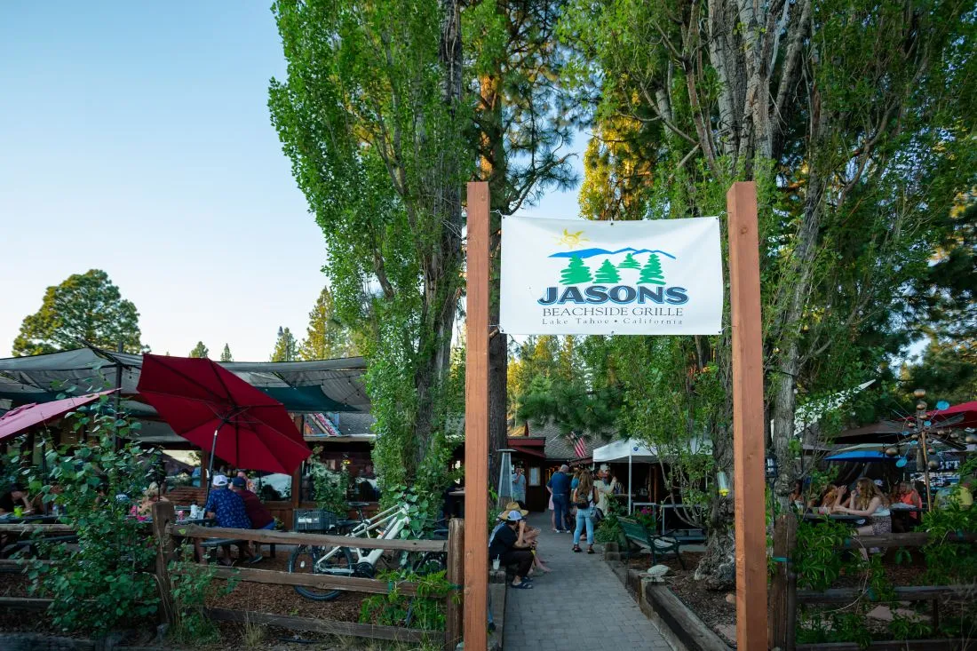 Signage for Jason's Beachside Grille in Kings Beach, California, with outdoor seating and shaded umbrellas in a relaxed atmosphere.