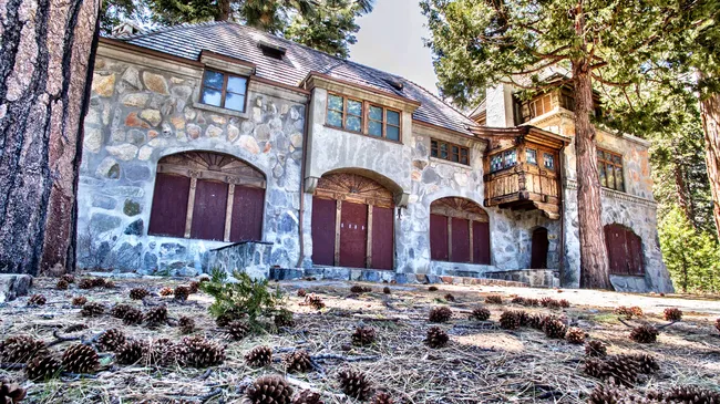 Close-up view of the historic stone Vikingsholm Castle surrounded by pinecones and tall trees in Lake Tahoe.