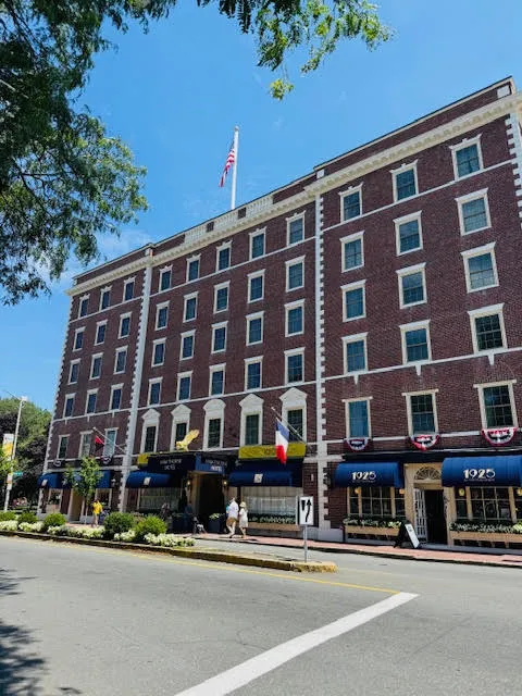 Historic red-brick Hawthorne Hotel in Salem, Massachusetts, with blue awnings, American flags, and people walking outside.