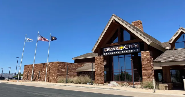 Cedar City Regional Airport building with stonework design and flags flying under a clear blue sky.